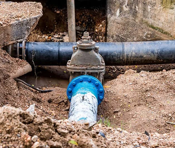 Blue and white water pipe installed in the ground, representing our Drain and Sewer Line Services.