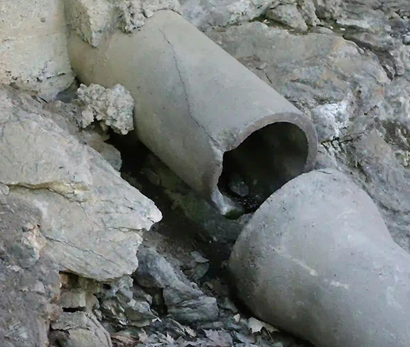 Pipe embedded in a rock wall, symbolizing expert sewer line thawing and repair services for efficient solutions.
