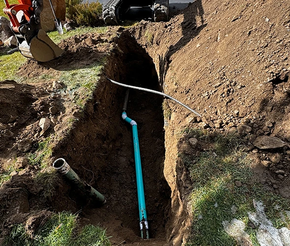 An excavator digging trench and placing pipelines, showcasing expertise in underground main line repairs.