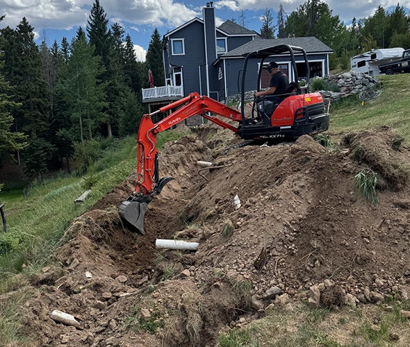 A man uses an excavator on a dirt hill, demonstrating efficient sewer line thawing services in a construction setting.