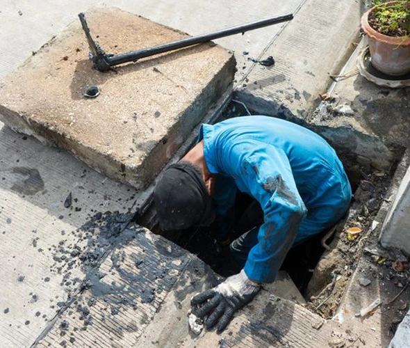 A technician working on a sewer drain, showcasing expertise in emergency water line repair services.